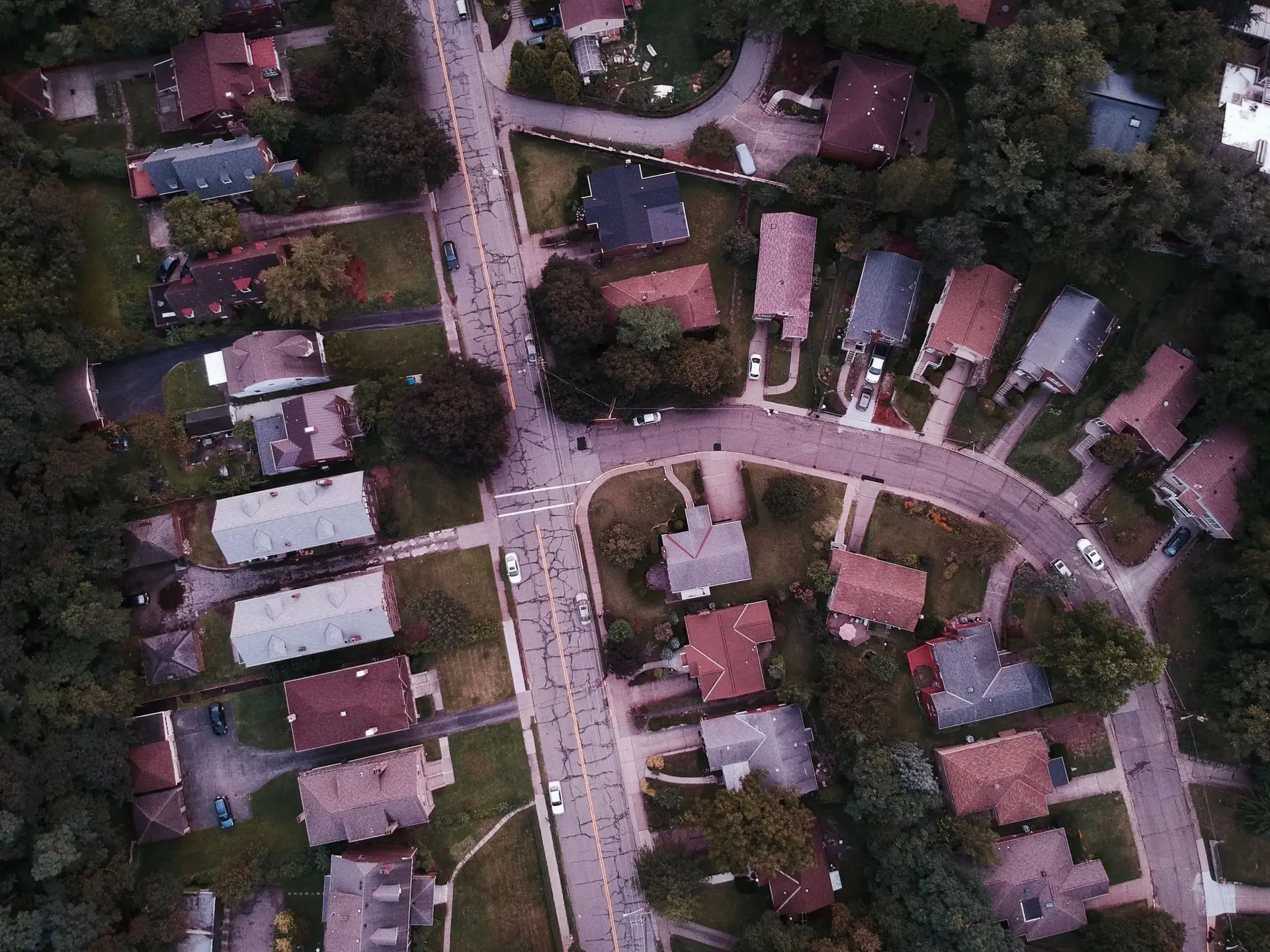 Rooftops along curving suburban streets seen from above