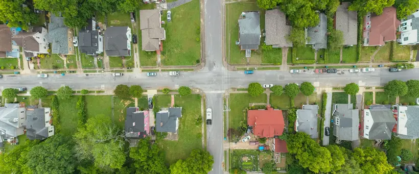 Aerial view of a street intersection lined with houses and trees