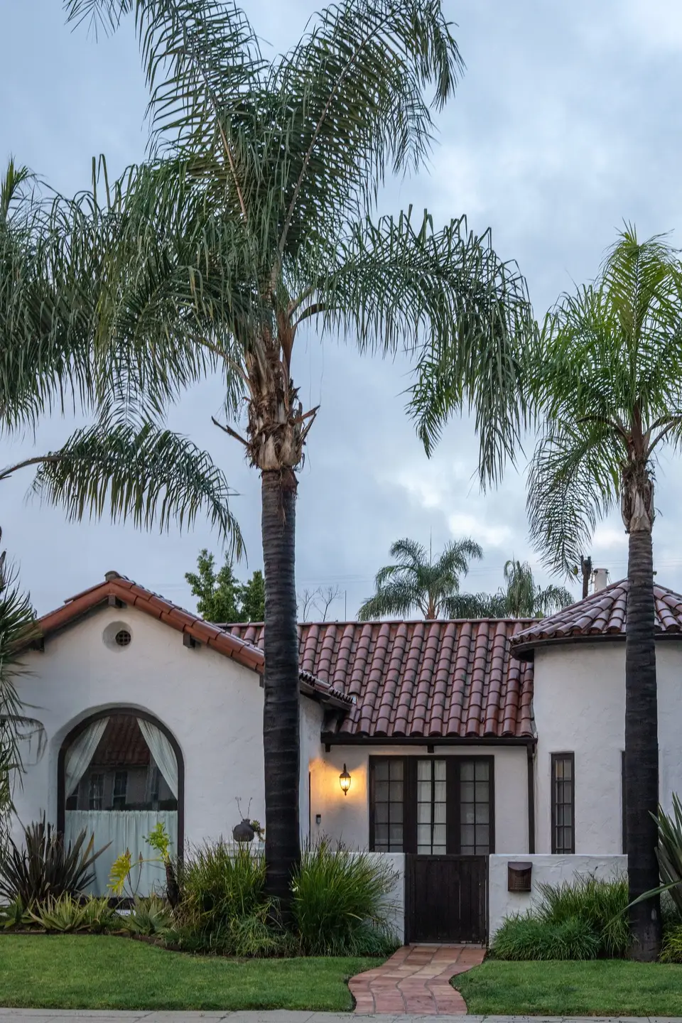 Spanish-style home with a tile roof and palms