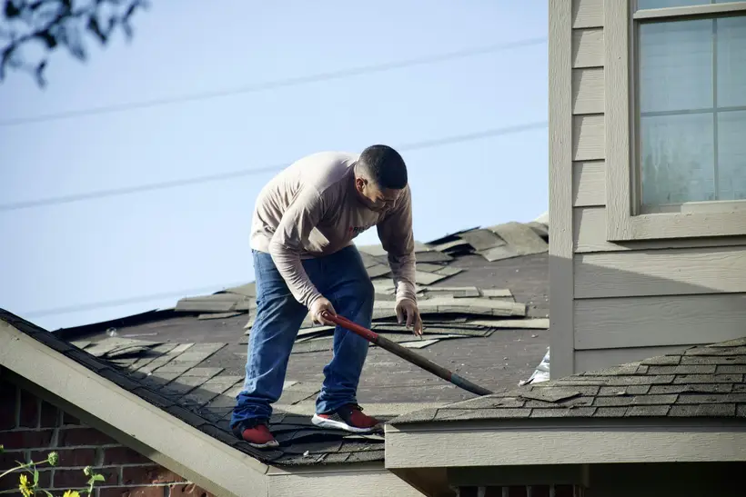 Roofer prying off old shingles